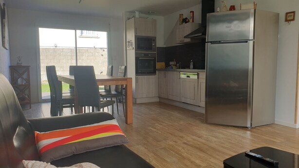 A modern kitchen with a refrigerator, oven, and microwave. There is a dining area with a table and chairs. - House equipped for 1-8 people (modular) (Montfarville)