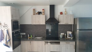 A modern kitchen with light wood cabinets, a black range hood, stainless steel appliances, and a dishwasher. - House equipped for 1-8 people (modular) (Montfarville)