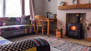 Ein gemütliches Wohnzimmer mit einer Couch, einem Holzstuhl, einem Kamin und einem Bücherregal.