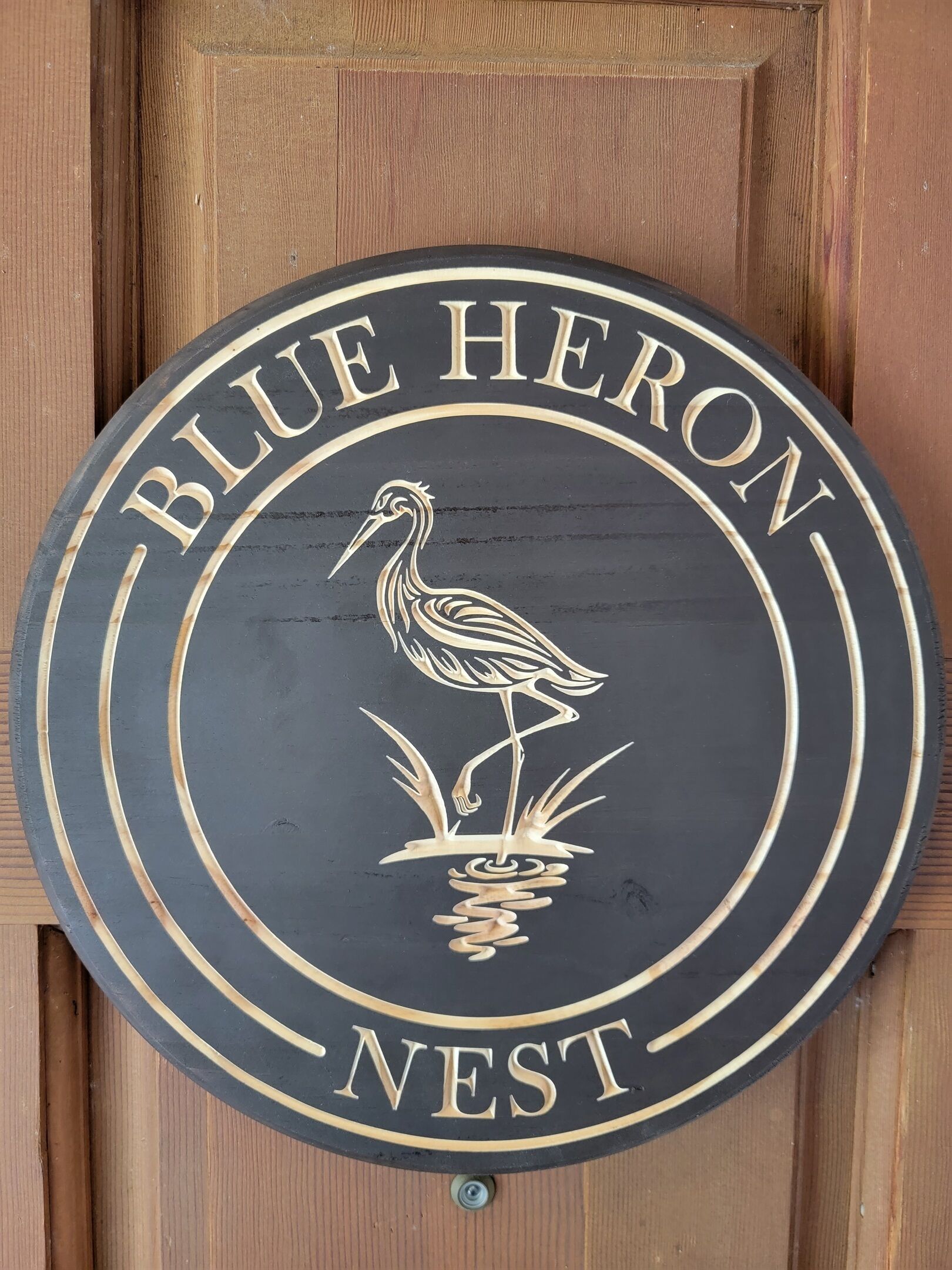 A circular sign with a bird illustration and the text "BLUE HERON NEST".