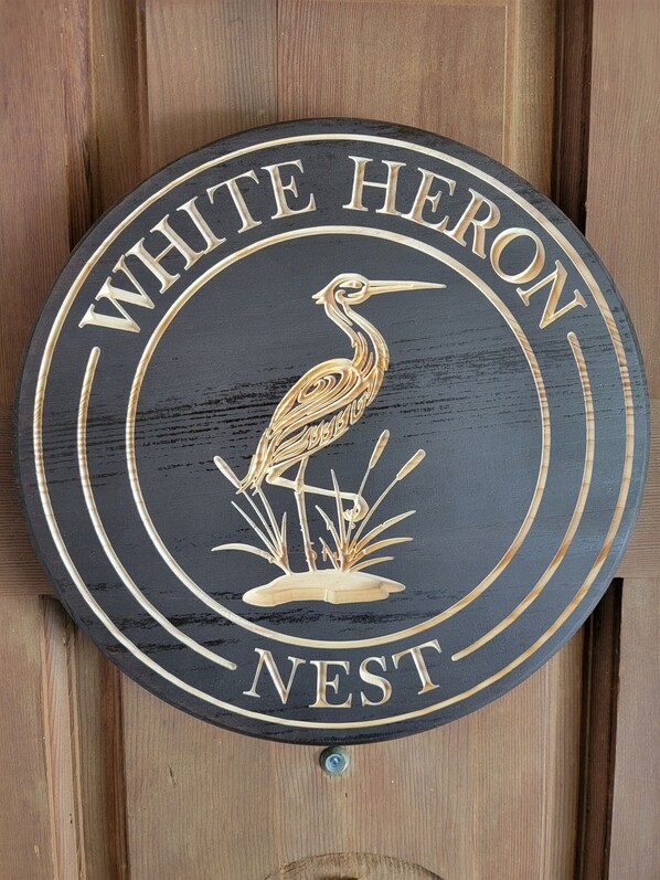 A circular sign with a bird illustration and the text "WHITE HERON NEST".