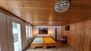 Een kamer met een houten plafond, een bed met een gele deken, een schilderij aan de muur en een kroonluchter.