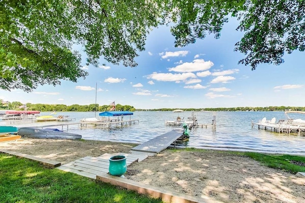 A lakeside dock with boats, a grassy area, and a clear sky.