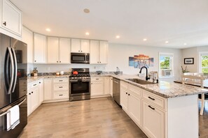 A modern kitchen with white cabinetry, stainless steel appliances, and a marble countertop. - Lake Daze | Lakefront Powers Lake Home, Sleeps 11 (Genoa City)