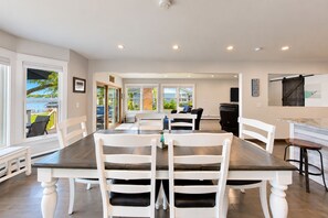 Comedor con una mesa grande y sillas, espacio de cocina con una parrilla, y vista al exterior.