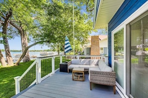 A deck with a sofa, a small table, and a striped umbrella.