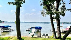 A lakeside dock with boats, a covered seating area, and a grassy area. - Lake Daze | Lakefront Powers Lake Home, Sleeps 11 (Genoa City)