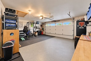 A garage with a workout area, including a bench press, weight rack, and various exercise equipment. - Lake Daze | Lakefront Powers Lake Home, Sleeps 11 (Genoa City)
