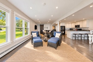 A spacious living area with a large window, a fireplace, and a kitchen with modern appliances.