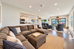 A spacious living area with a sectional sofa, a dining table with chairs, and a view of the outdoors. - Lake Daze | Lakefront Powers Lake Home, Sleeps 11 (Genoa City)