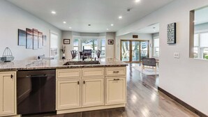 A modern kitchen with a large island, built-in dishwasher, and a dining area with a view. - Lake Daze | Lakefront Powers Lake Home, Sleeps 11 (Genoa City)