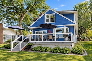 A two-story house with a blue exterior, a covered porch with outdoor furniture, and a staircase leading to the entrance. - Lake Daze | Lakefront Powers Lake Home, Sleeps 11 (Genoa City)