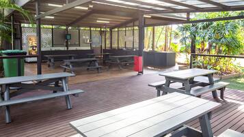 An outdoor covered patio area with picnic tables and a seating area.