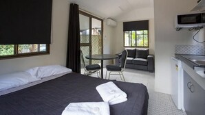 Una habitación de hotel con cama, una pequeña mesa de comedor, un sofá y una kitchenette.