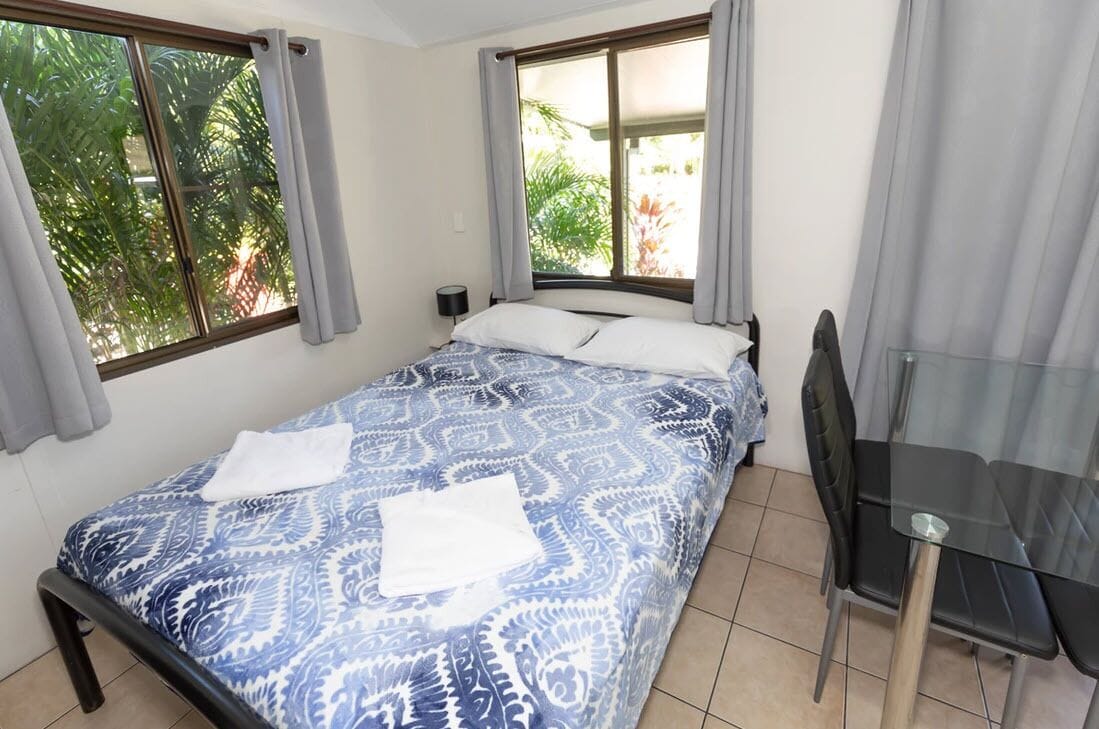 A bedroom with a bed, a small table, and chairs.