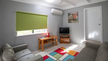 Un soggiorno con divano, televisione, tavolino e tappeto colorato.