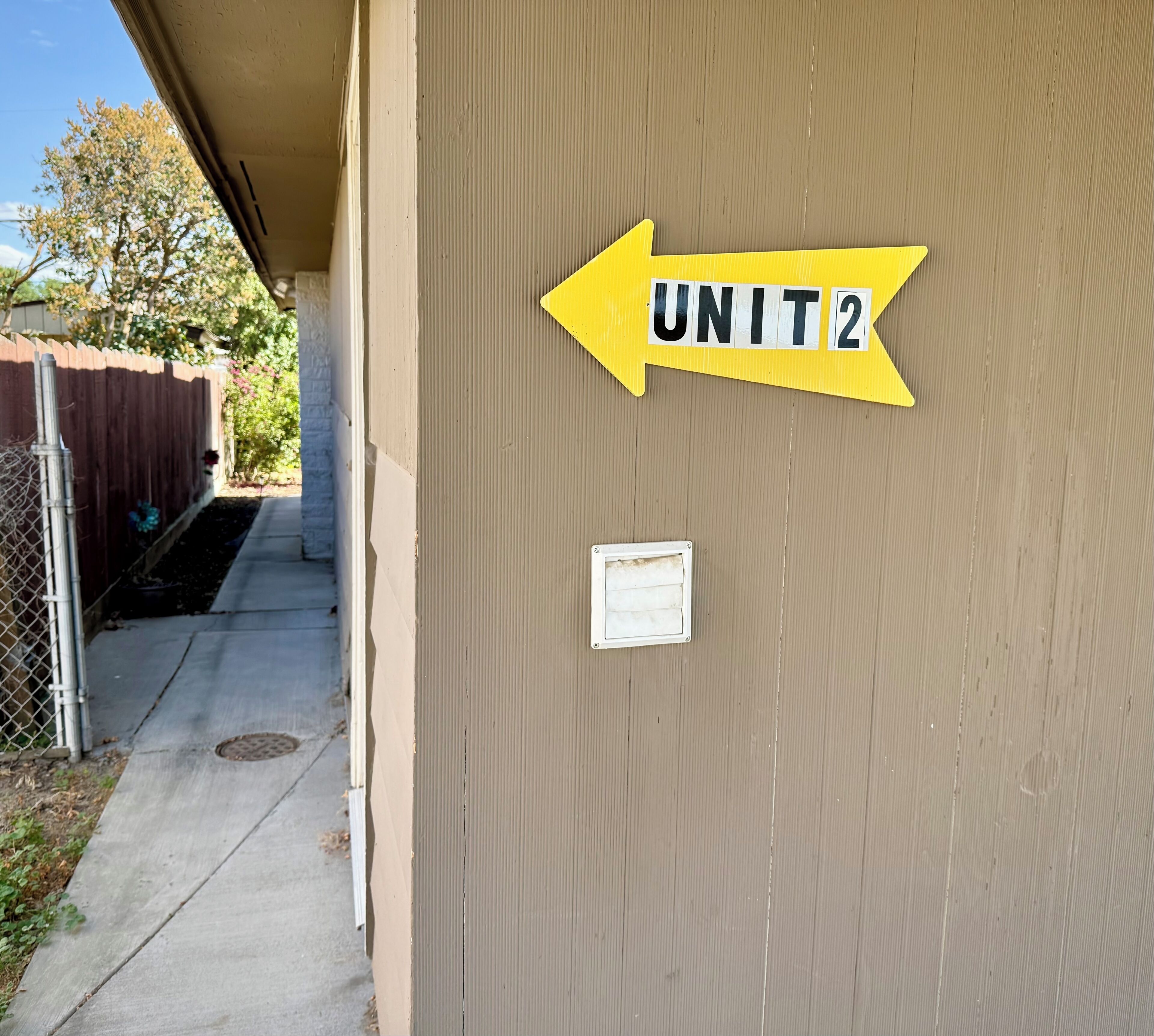A building exterior with a sign indicating 'UNIT 2' and a directional arrow.
