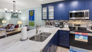 Eine moderne Küche mit blauen Schränken, einer Edelstahl-Spüle und einer Mikrowelle.
