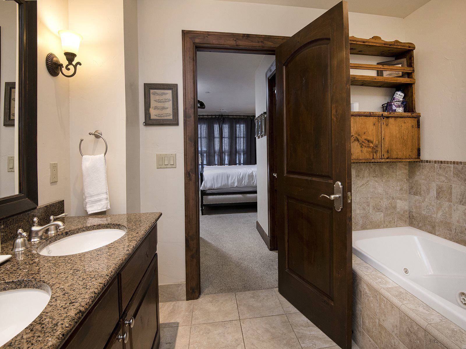 Un baño con dos lavamanos, un espejo grande, una puerta de madera y una bañera.