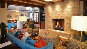 A cozy living room with a stone fireplace, blue sofas, and a patterned armchair.