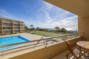A balcony with a pool, a table, and chairs.