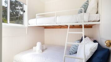 A bunk bed with a ladder, a window, and a door with a brass handle.