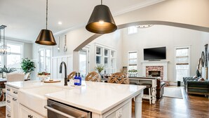 A spacious kitchen with a large island, modern pendant lights, and a fireplace. - Gated Private Estate With Pool, Hilltop Views, and Game Room on 8 acres (Thompson's Station)