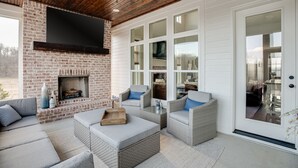 A cozy living room with a brick fireplace, wicker furniture, and large windows. - Gated Private Estate With Pool, Hilltop Views, and Game Room on 8 acres (Thompson's Station)