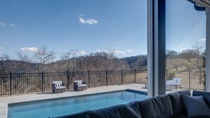 A pool area with a view of a fenced yard and trees. - Gated Private Estate With Pool, Hilltop Views, and Game Room on 8 acres (Thompson's Station)