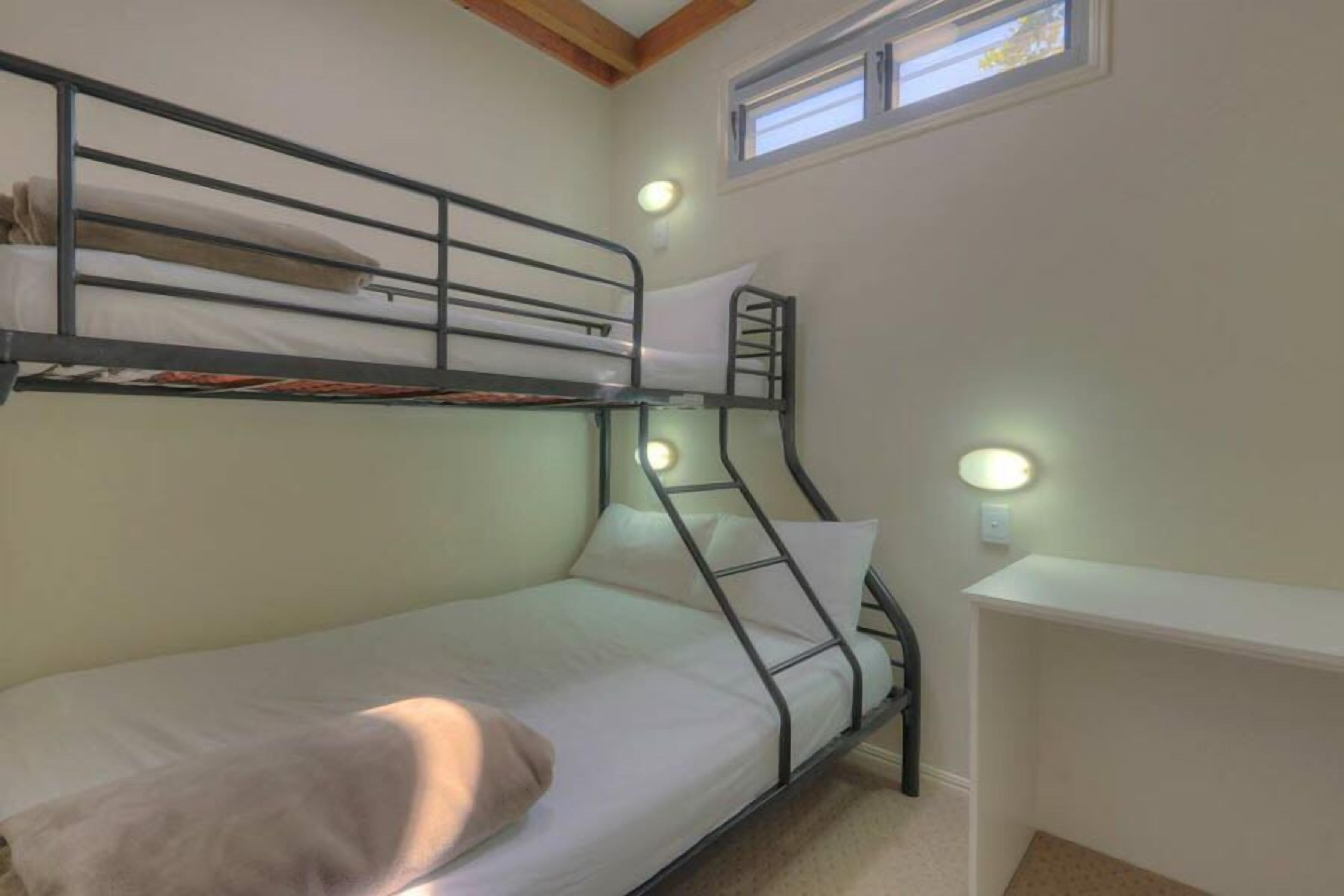 Une chambre avec un lit superposé, un bureau et deux lampes de chevet.