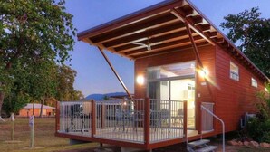 A small, single-story wooden cabin with a covered porch and a staircase leading to the entrance. - Tasman Holiday Parks - Rollingstone (Rollingstone)