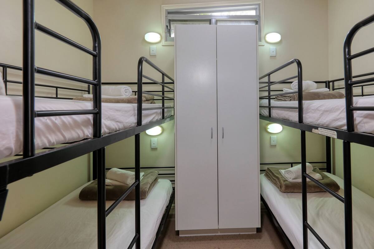 A bunk bed room with a wardrobe and two bedside lamps.