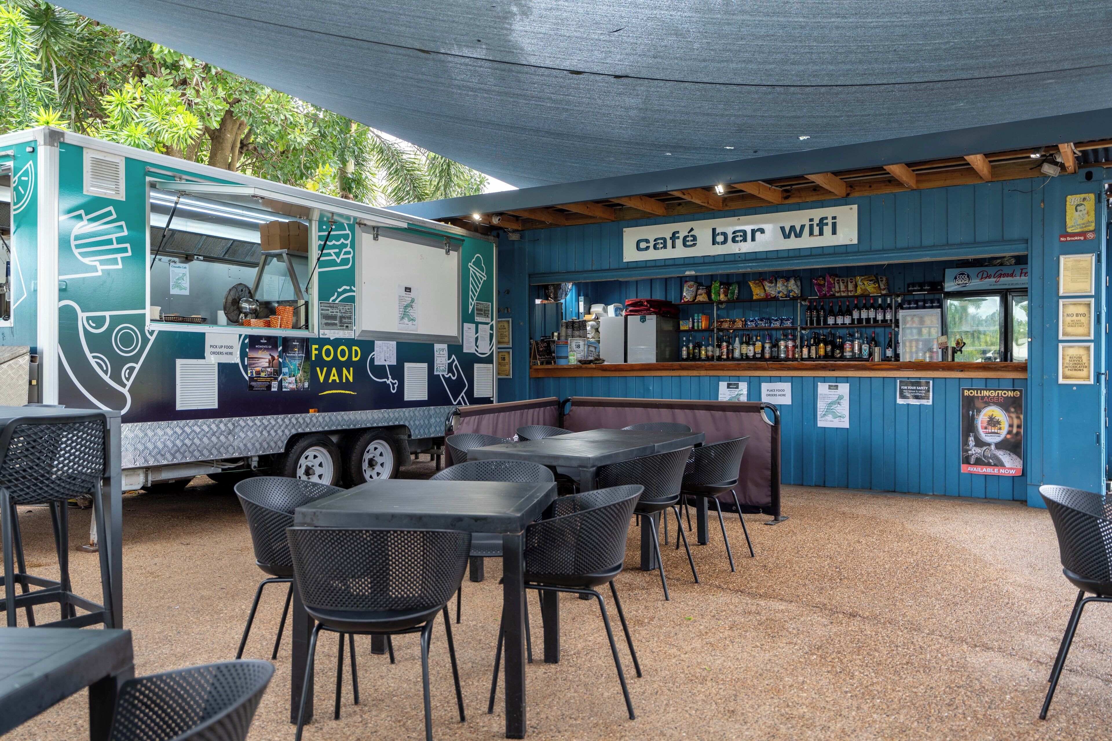 A café bar with outdoor seating, a food truck, and a bar area with a sign indicating wifi availability.