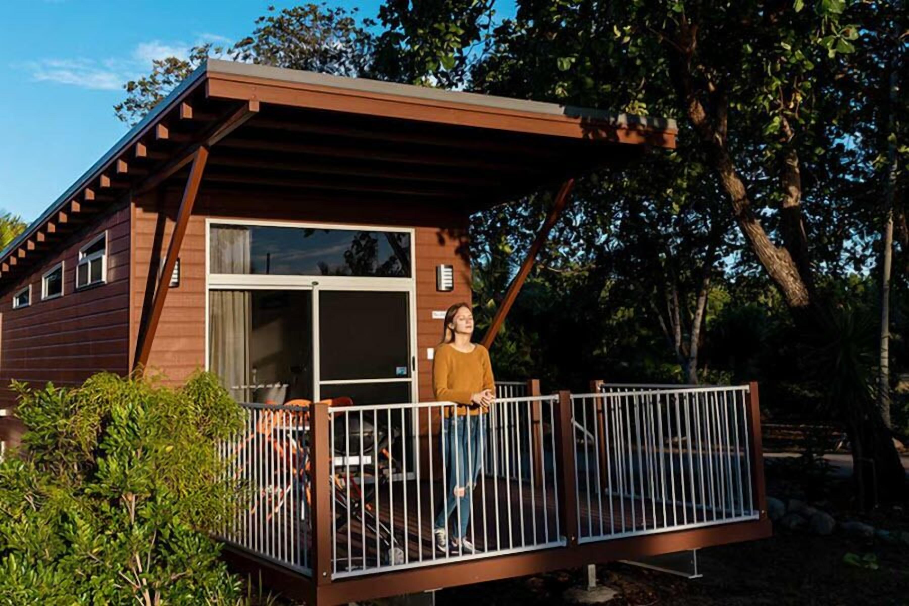 A cabin with a balcony, a sliding glass door, and a small outdoor seating area.