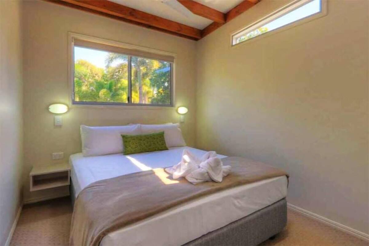 A bedroom with a bed, a window, and a nightstand.