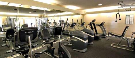 Une salle de sport équipée de divers appareils de cardio, notamment des tapis de course et des vélos elliptiques.