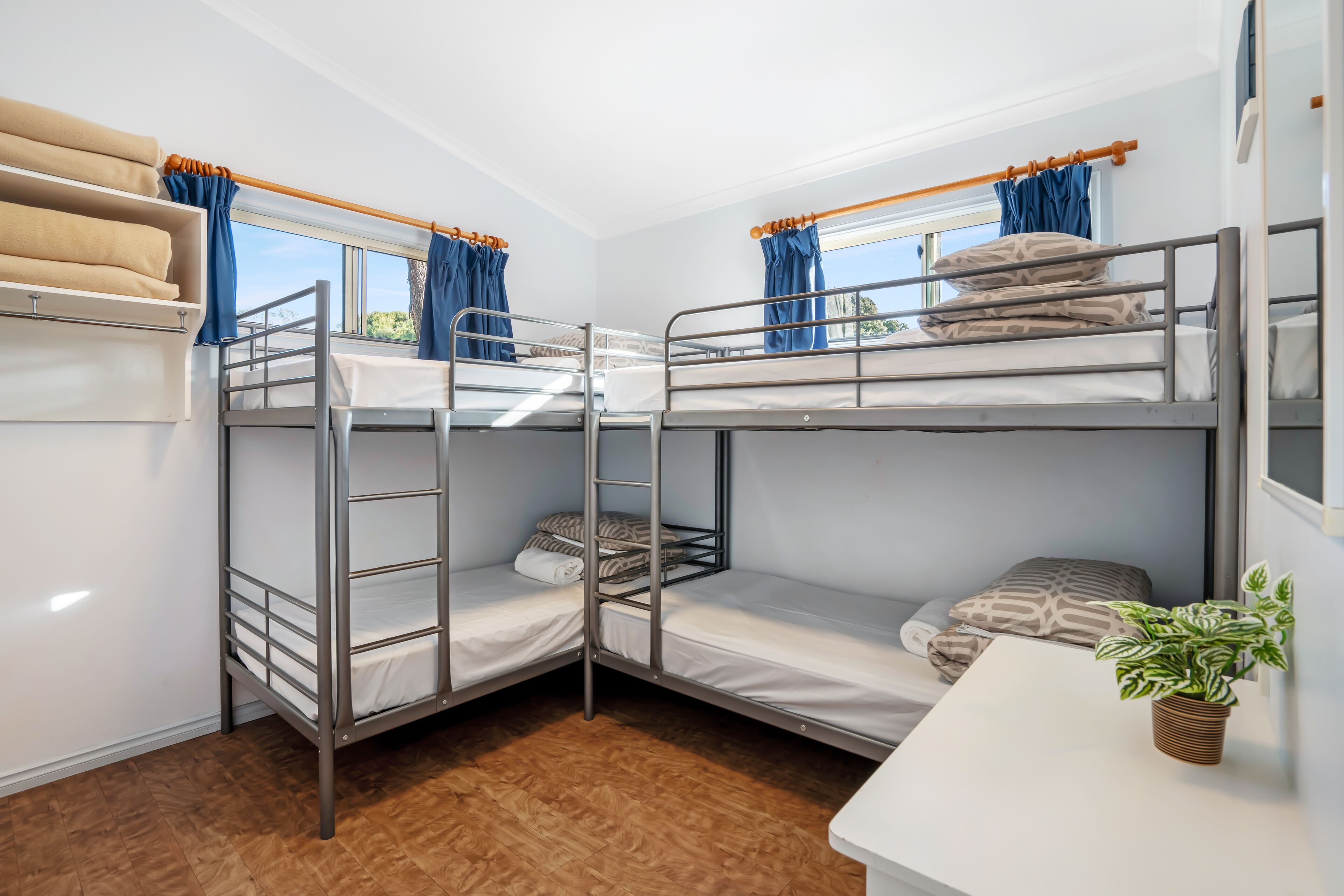 Een slaapkamer met stapelbedden, een tafeltje en een potplant.