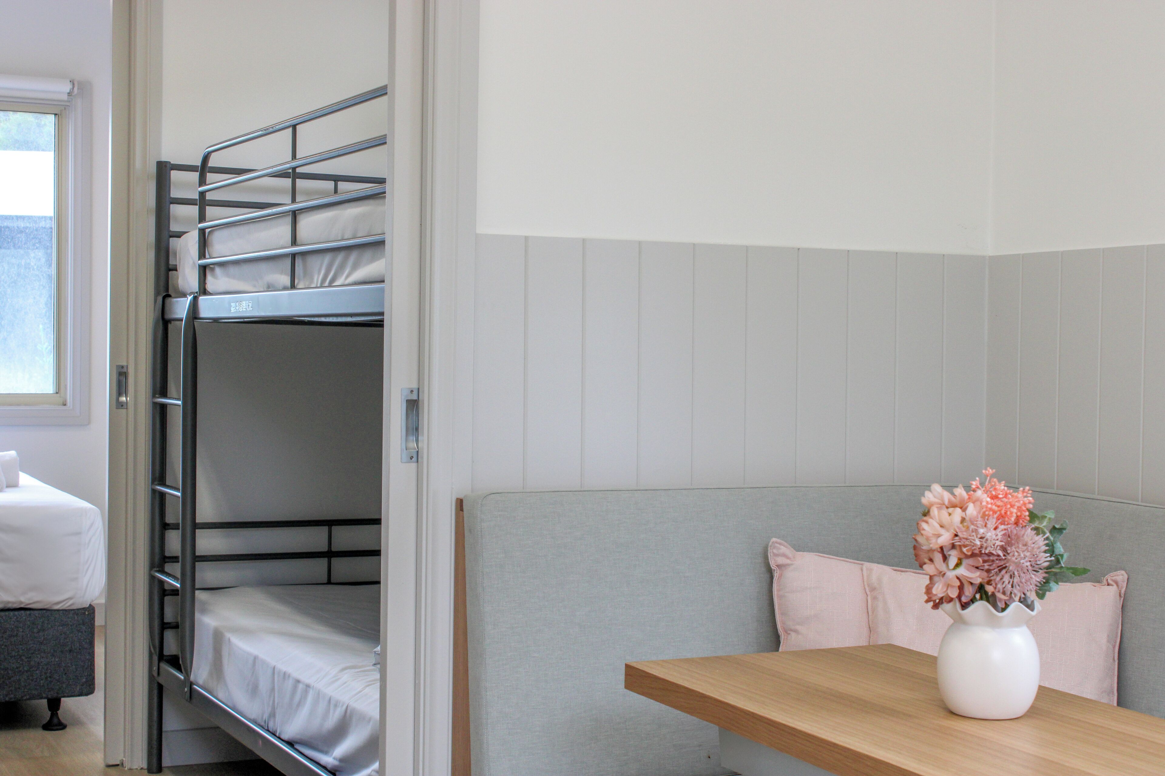 A bunk bed with a pillow and a vase with flowers on a table.