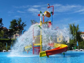 A water park with a water slide, a pool, and a red boat. - Holiday apartment with outpool (Castelnuovo del Garda)