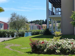 Een woonwijk met kleurrijke huizen, een verzorgd gazon en een balkon aan een van de gebouwen.