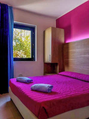 A hotel room with a bed, a window, and a wooden wardrobe. - Holiday apartment with outdoor pool (Castelnuovo del Garda)