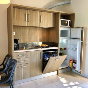 A compact kitchen with wooden cabinets, a microwave, a refrigerator, and a dishwasher. - Holiday apartment with outdoor pool (Castelnuovo del Garda)