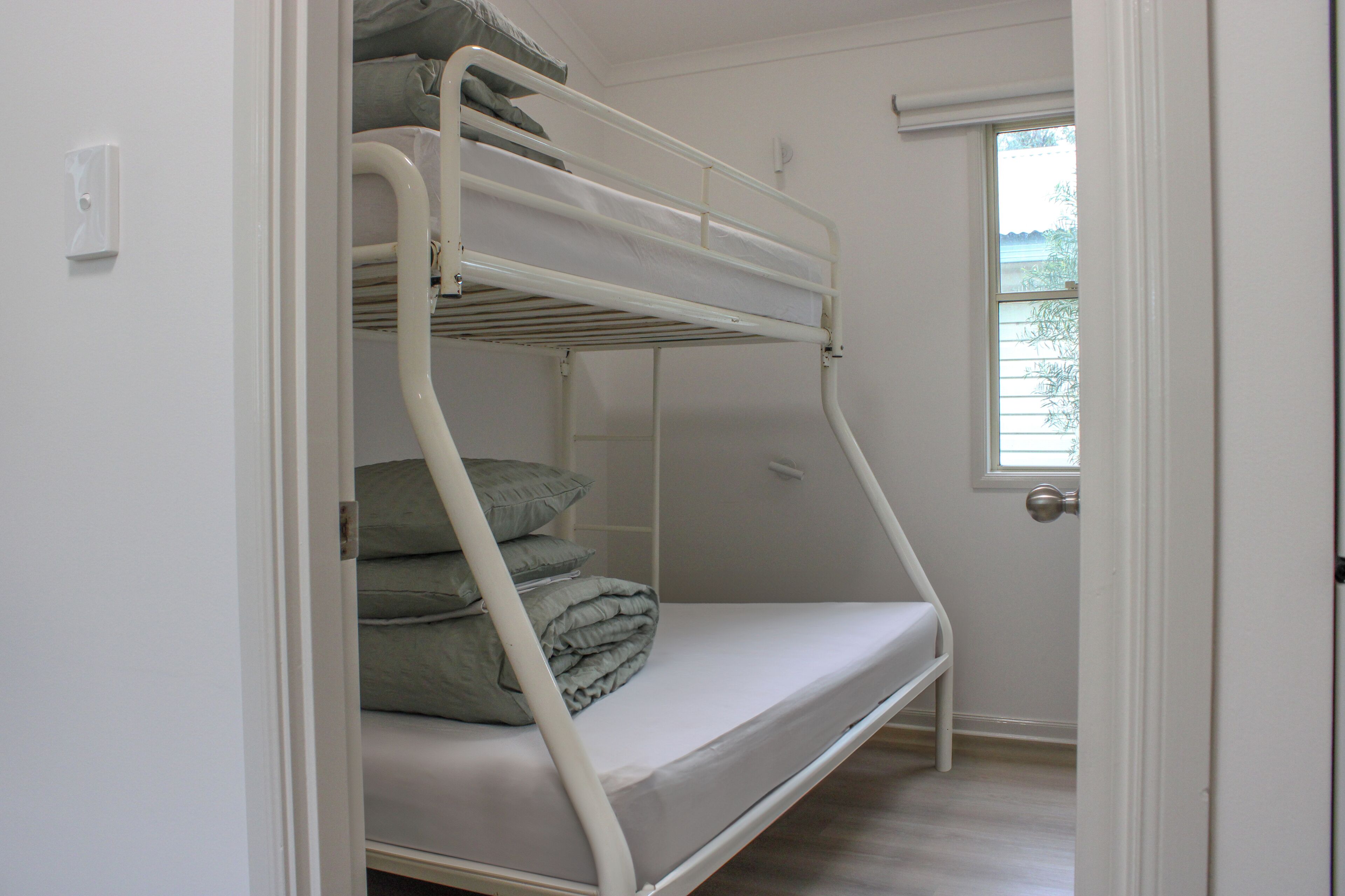 Ein Stockbett mit Kissen, einem Fenster und einer Tür.