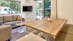 A modern living room with a sofa, a round coffee table, and a wooden dining table. - Tasman Holiday Parks - Yallingup Caves (Yallingup)