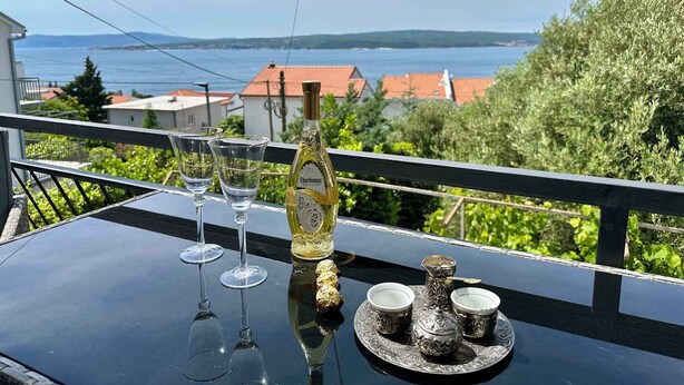 Een balkon met een tafel gedekt voor twee personen, met een fles Chardonnay, twee wijnglazen en een zilveren theeservies.