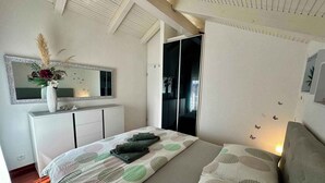 Een slaapkamer met een bed, een kaptafel, een spiegel en een kledingkast.
