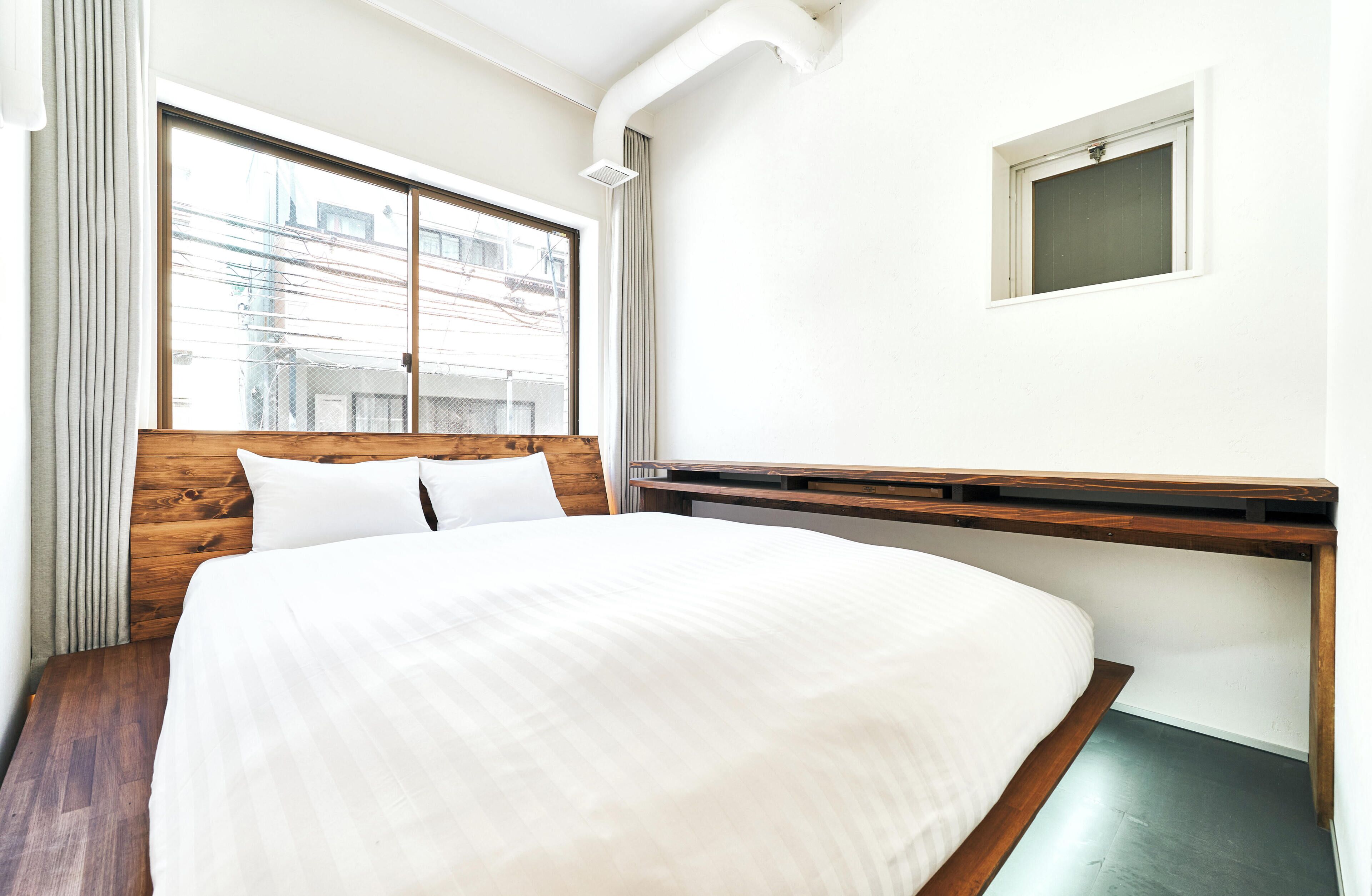 Un dormitorio con una cama grande, cabecera de madera, una ventana con cortinas y un ventanal en la pared.