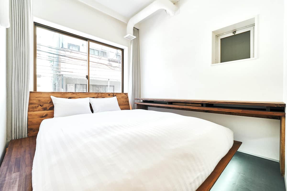 Un dormitorio con una cama grande, cabecera de madera, una ventana con cortinas y un ventanal en la pared.