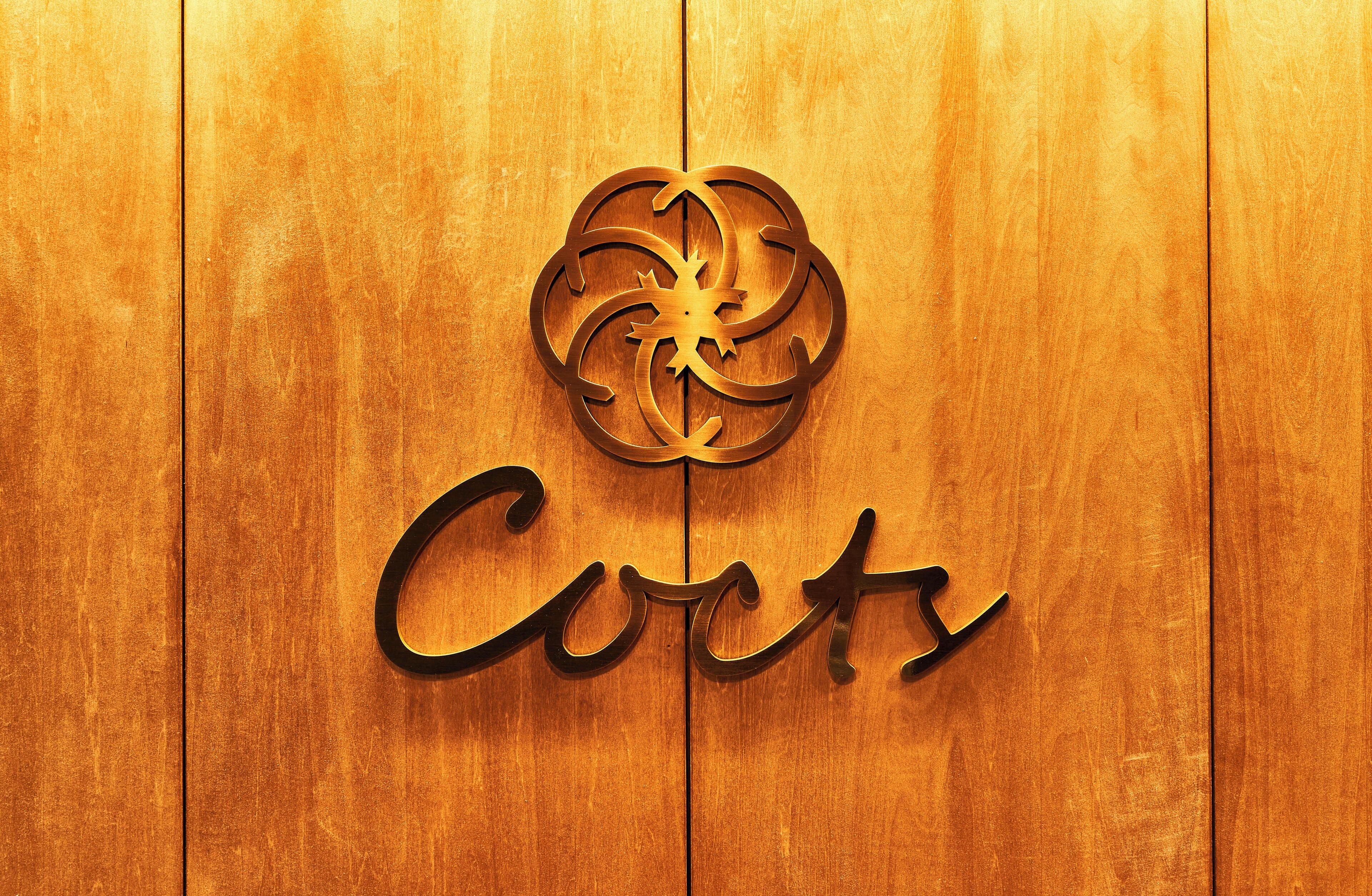 A wooden door with a decorative metal emblem and the word "Corts" engraved on it.