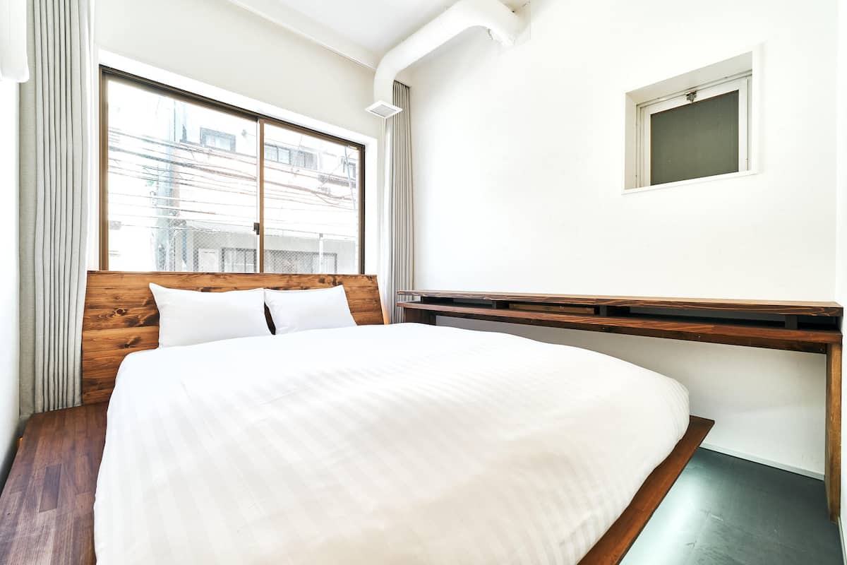 Un dormitorio con una cama grande, cabecera de madera, una ventana con cortinas y un ventanal en la pared.